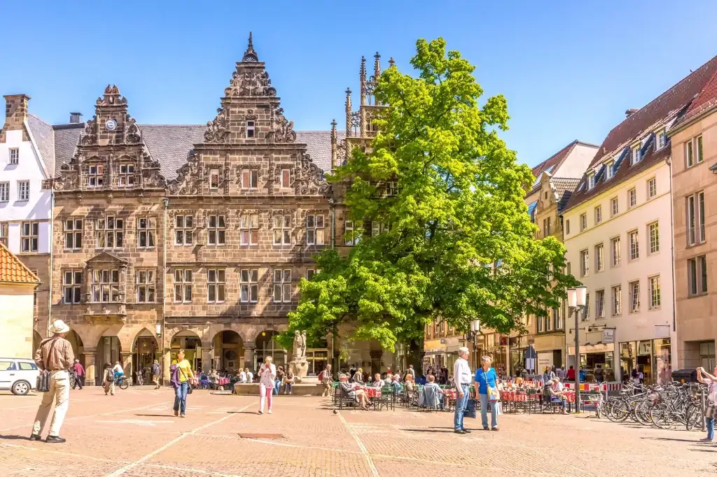 Marktplatz mit Touristen bei einem Besuch mit Hotel in Münster bei Sonnenschein