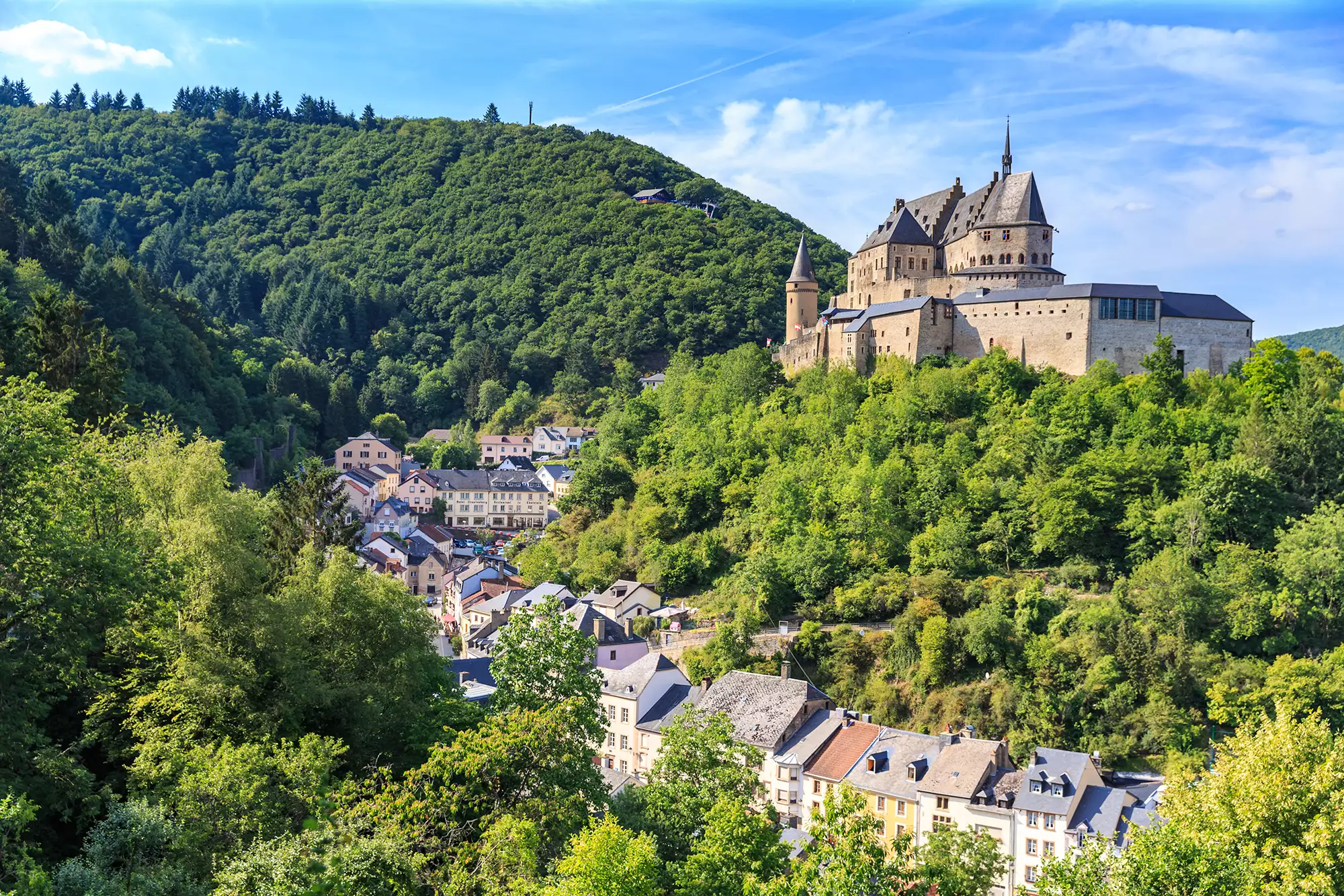 Blick auf die von Bäumen eingebettete Burg Vianden bei einem Luxemburg Städtetrip