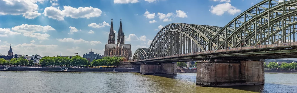 Blick vom Rhein auf Kölner Dom vor strahlend blauen Himmel mit Kumuluswolken